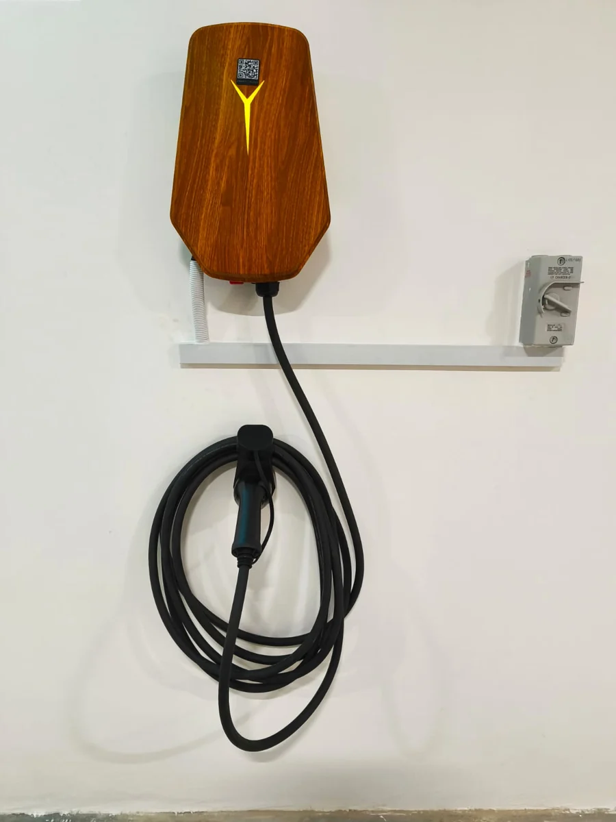 A wood-grain HiCi charger above a white cable rail that runs to an isolator.