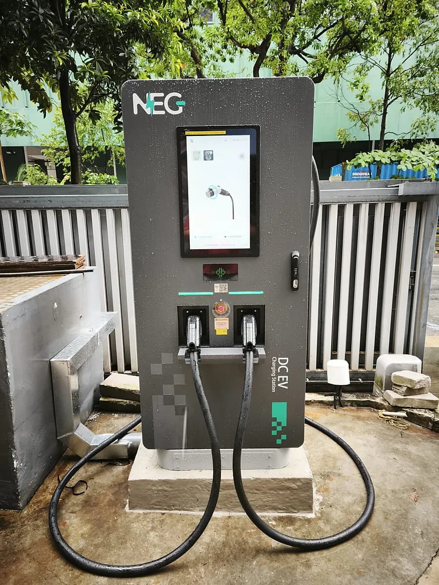 A NEG DC fast charger on a concrete plinth, its two cables running to the ground.