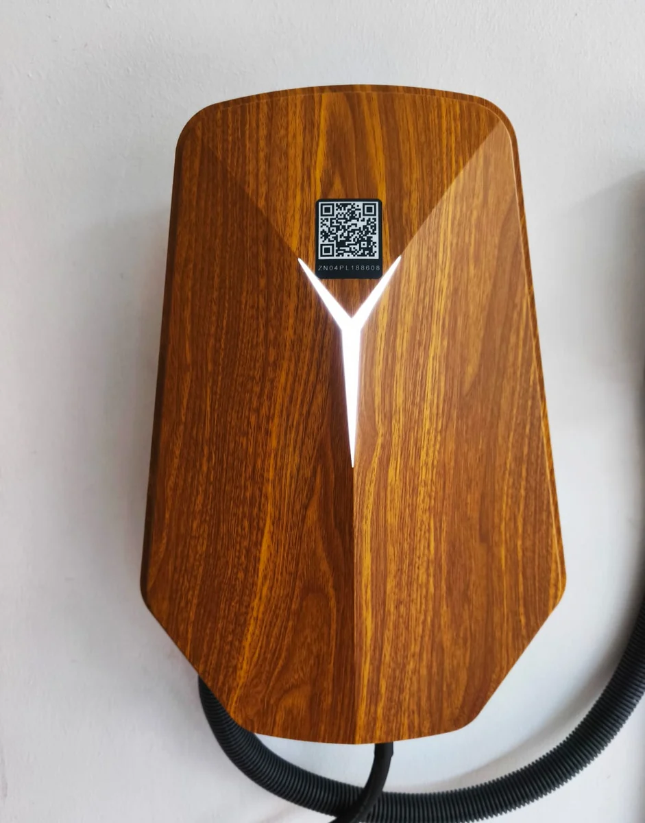 Close view of a wood-grain HiCi charger showing the faceted shell, the small QR label and the white Y light, with flexible conduit at the side.